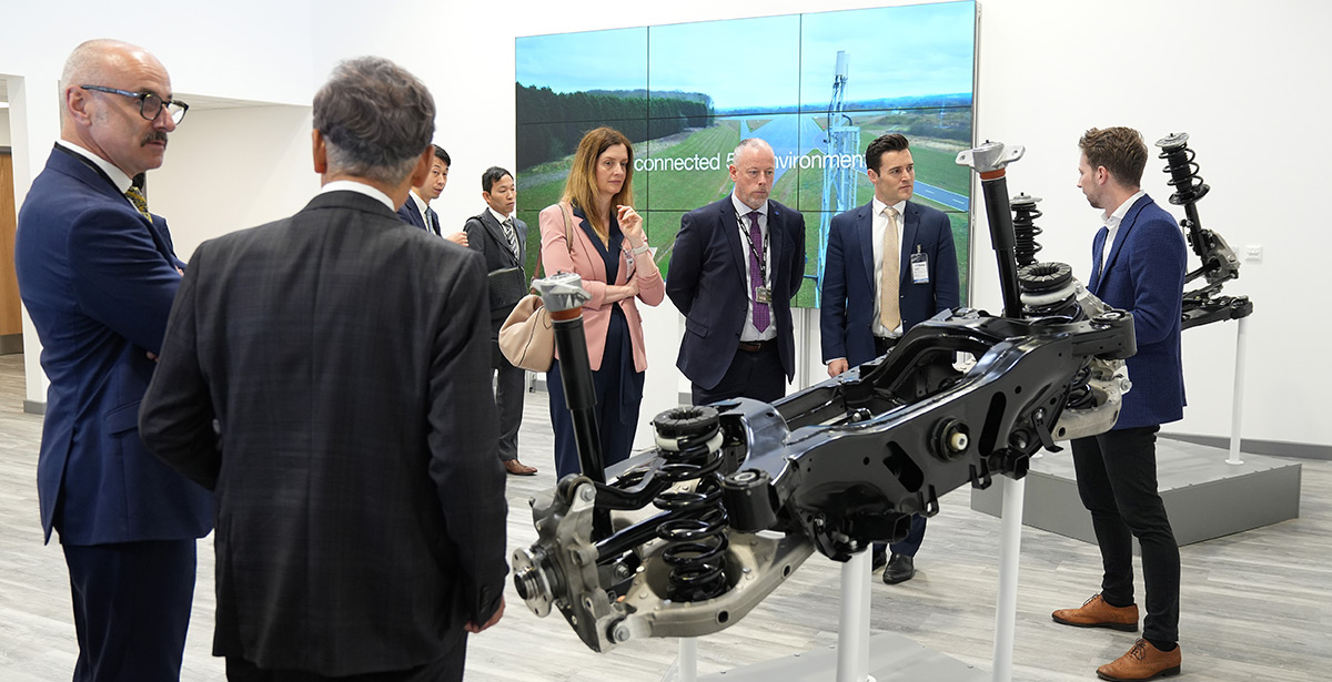 A group of people standing a round a vehicle chassis on display