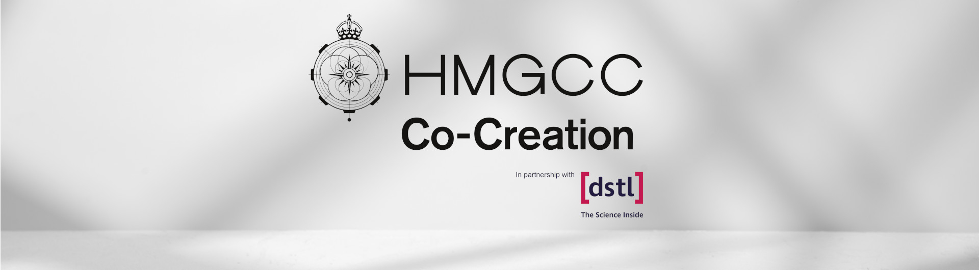 The HMGCC co-creation logo on s grey background